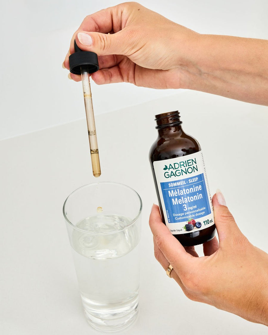 Hands holding a dropper over a glass of water, next to a bottle of liquid melatonin