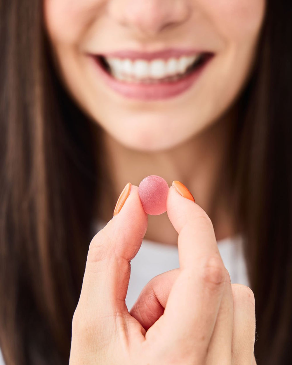 Gummy held between two fingers in front of a person