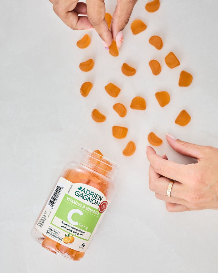 Hands arranging vitamin C gummies around their Adrien Gagnon container